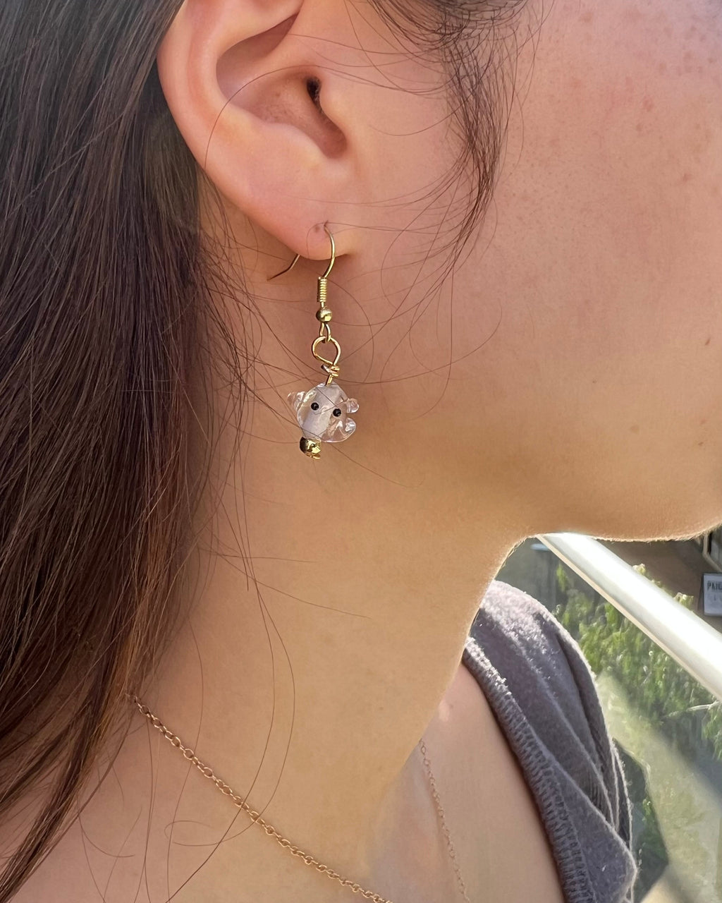 Close-up of a person wearing gold earrings with floral designs.